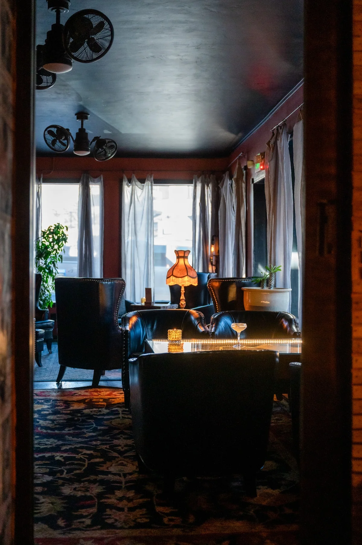 Cozy seating nook lit by a brass lamp in the speakeasy